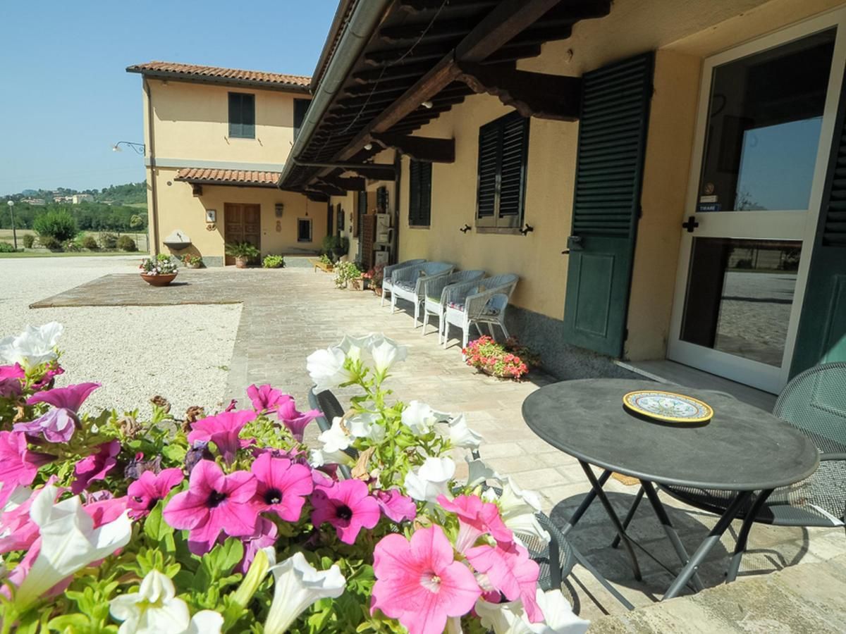 Accoglienza semplice in un agriturismo immerso nelle colline umbre, circondato da un ampio giardino con fiori.