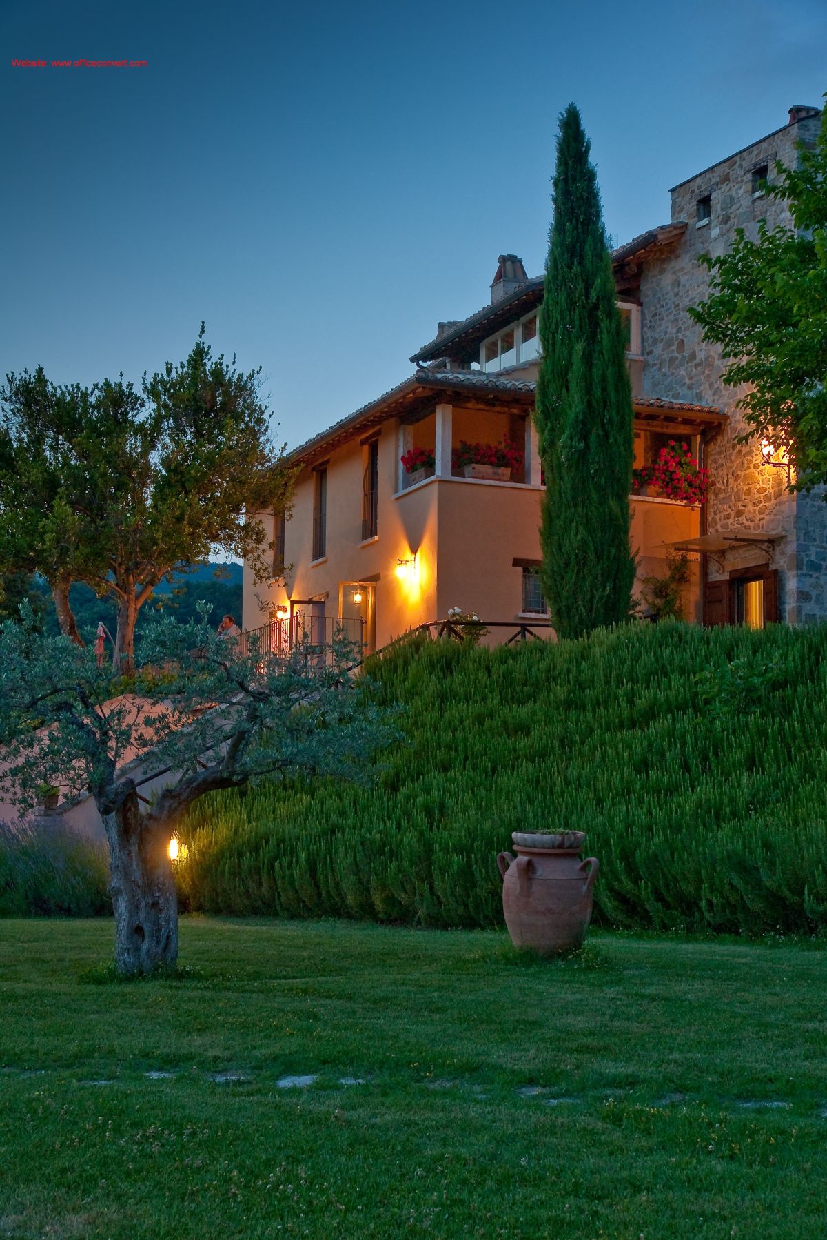 Une villa entourée d'arbres et de plantes, éclairée par la lumière chaude du coucher de soleil.