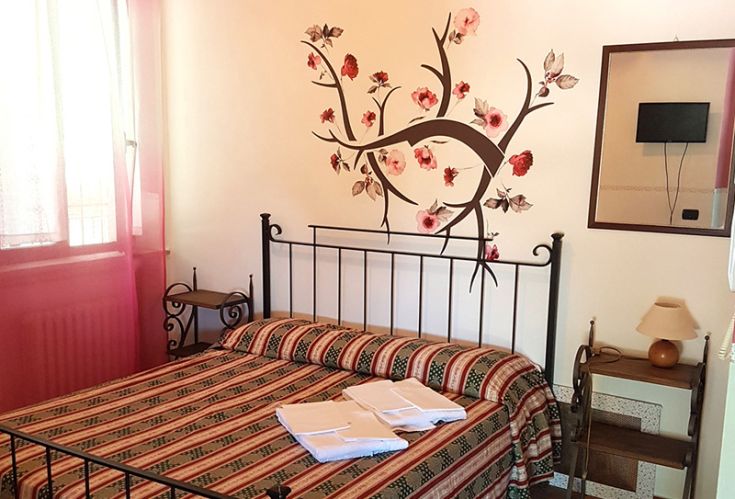 Camera ospitale con decorazioni floreali, affacciata su un paesaggio verde, perfetta per una pausa tranquilla.