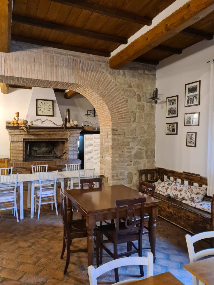 Spazio confortevole con camino, tavoli in legno e decorazioni, ideale per momenti di relax.