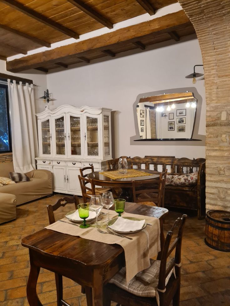 Un angolo di un agriturismo con tavoli in legno, creando un'atmosfera semplice e accogliente.