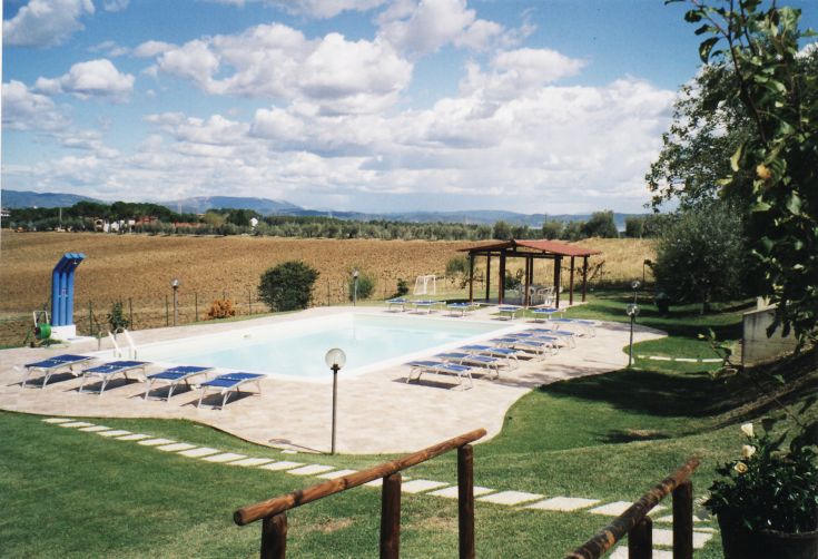 Schwimmbad in einem Bauernhof, umgeben von einer großen grünen Fläche, perfekt für Freizeit und Ruhe.