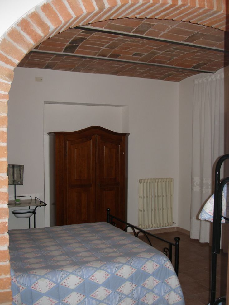 Ein einfacher Raum mit einem Holzbett und einem Kleiderschrank, gestaltet für einen gemütlichen Aufenthalt.