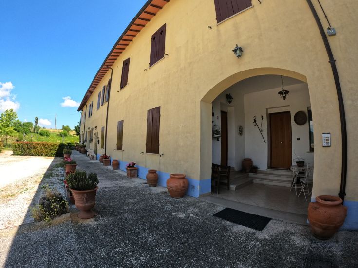 Agriturismo circondato da un ampio giardino con una piscina e spazi verdi ben curati.