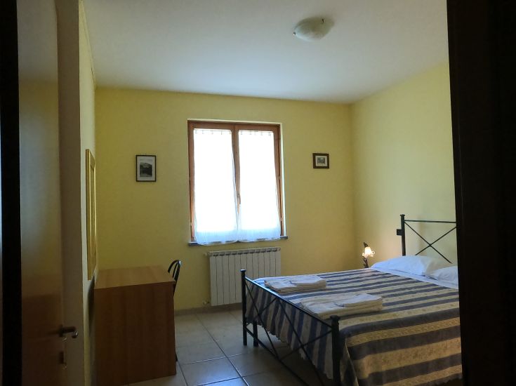 Camera accogliente in agriturismo, dotata di letti comodi e decorazioni sobrie, con una buona luce naturale.