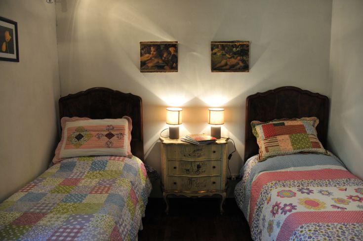 A simple room with side-by-side single beds, lamps, and wall decorations.