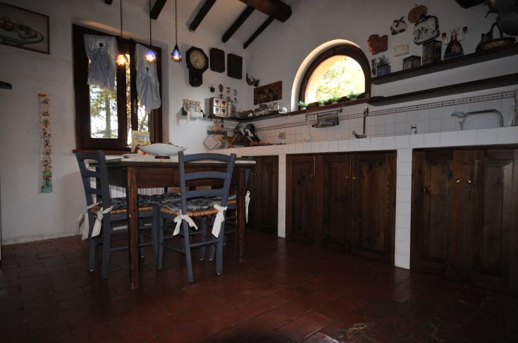 A simple kitchen in a farmhouse, decorated in wood, overlooking the surrounding natural landscape.