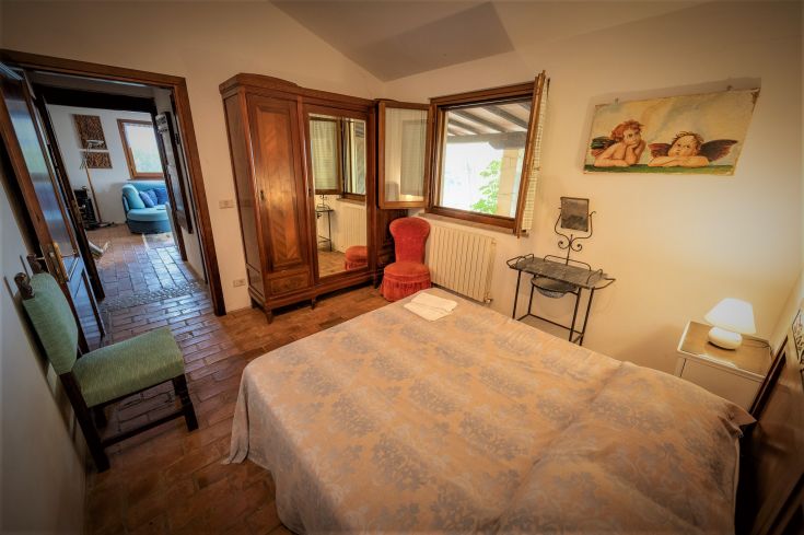 Cozy room with modest furnishings and a view of a serene Umbrian landscape.