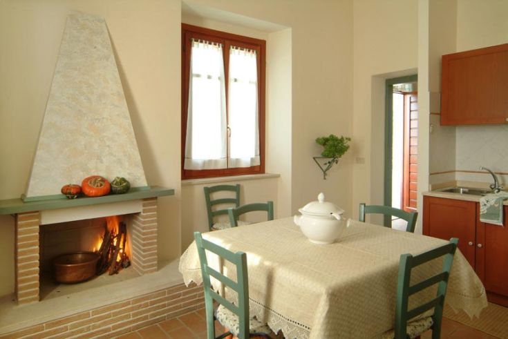 Un angolo di cucina semplice con un camino e un tavolo pronto per un pasto in compagnia.