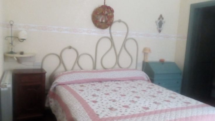 Camera semplice con letto matrimoniale, arredamento sobrio e dettagli vintage, situata in un agriturismo.
