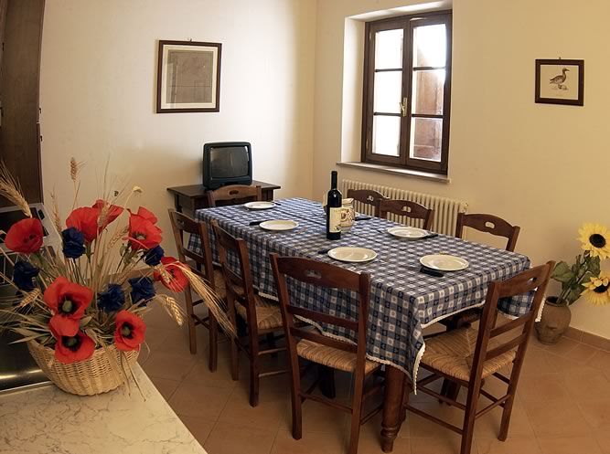 Living room with a dining table set for guests, adorned with simple, colorful flowers.
