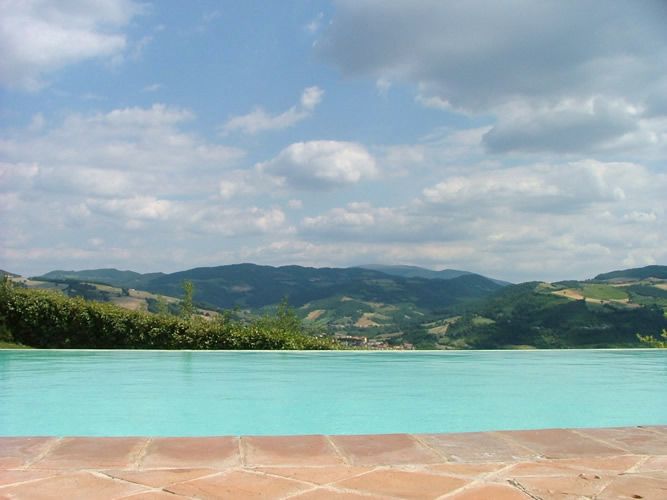 View of green hills and a clear sky, reflected in the transparent pool.