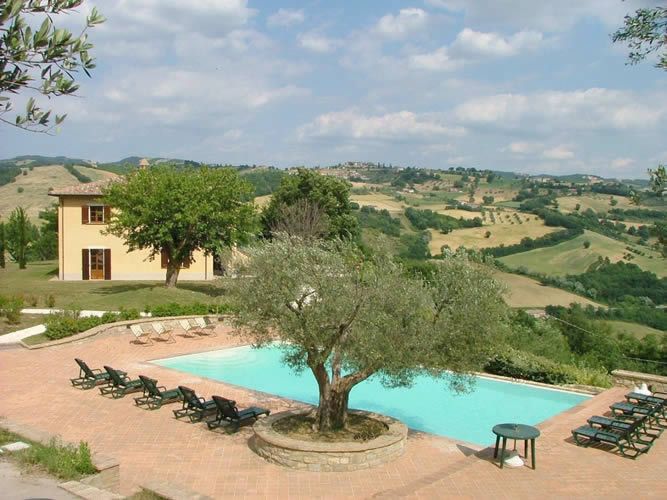 A villa in Umbria surrounded by olive trees, featuring an outdoor pool in the garden.