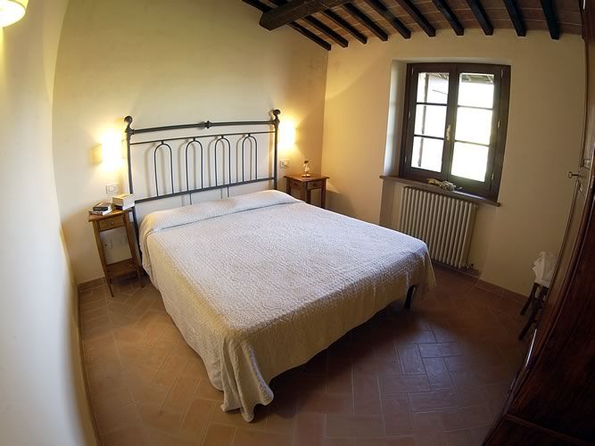 Cozy traditional Umbrian style room with a double bed and large windows for natural light.