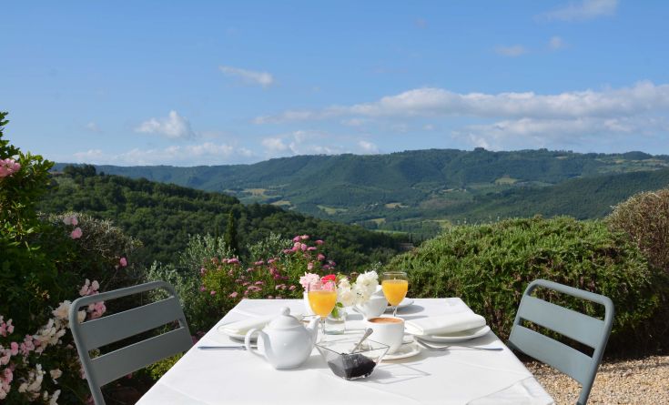 Frühstück im Freien, umgeben von grünen Hügeln und Blumen. Ein Moment der Gelassenheit in der Natur.