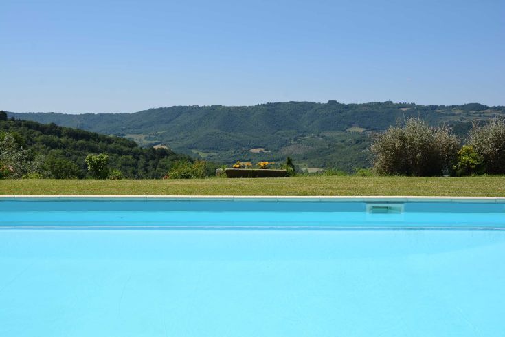 Ein blauer Pool befindet sich in der Nähe von grünen Hügeln, die bis zum Horizont reichen.