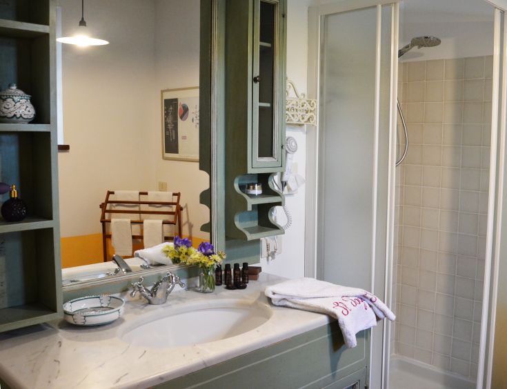 Ein gut eingerichtetes Badezimmer mit Duschkabine und grünen Holz-Möbeln, mit Blick auf ein ruhiges Gebiet.