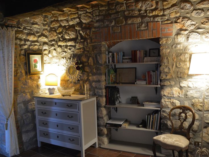 Innenraum eines Gebäudes mit Steinmauern und einem funktionalen Bücherregal, perfekt für entspannende Momente.