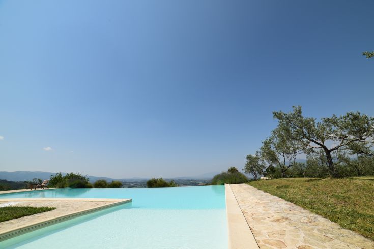 Infinity pool surrounded by the lush greenery of Umbria's hills, perfect for relaxation and scenic views.
