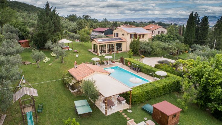 Rustic villa with a pool surrounded by greenery, offering relaxation areas in a serene environment.