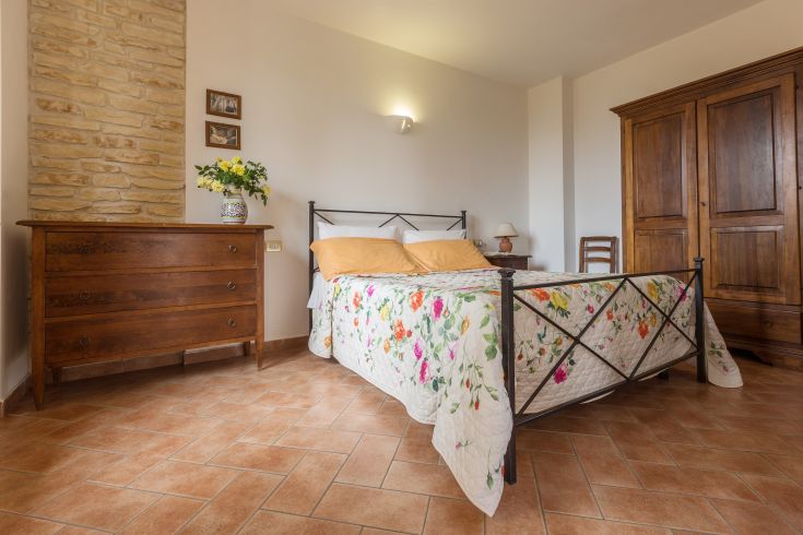 Simple bedroom featuring a double bed and wooden furniture. Light decorative elements and plenty of natural light.