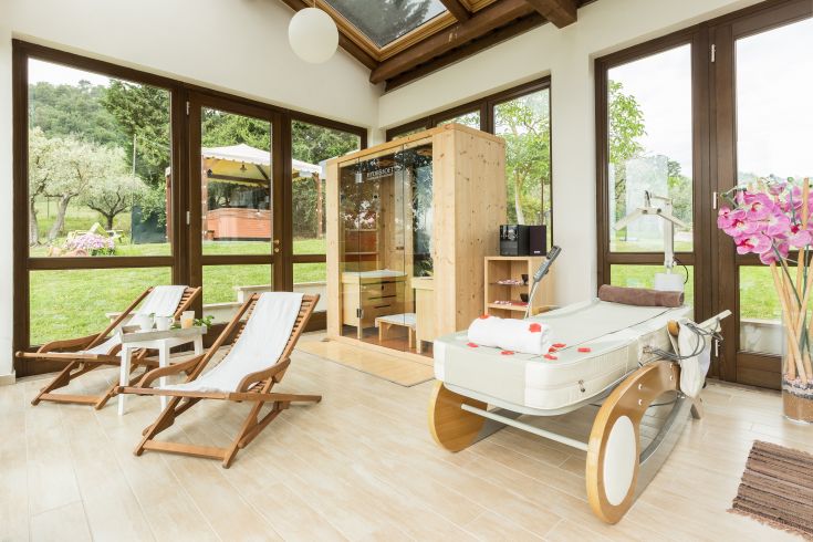 A tranquil environment featuring a wellness corner, loungers, and a view of a well-kept garden.
