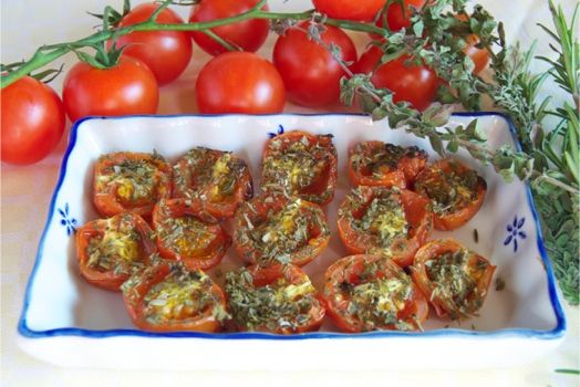 Pomodori cotti al forno con erbe aromatiche, presentati su un piatto bianco. Un piatto semplice e gustoso.