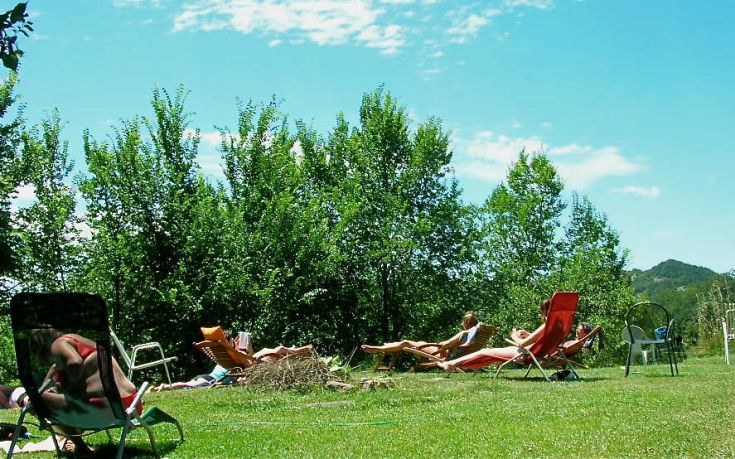 Un momento di relax immerso nella natura, con sedie a sdraio in un ambiente soleggiato e alberi verdi intorno.