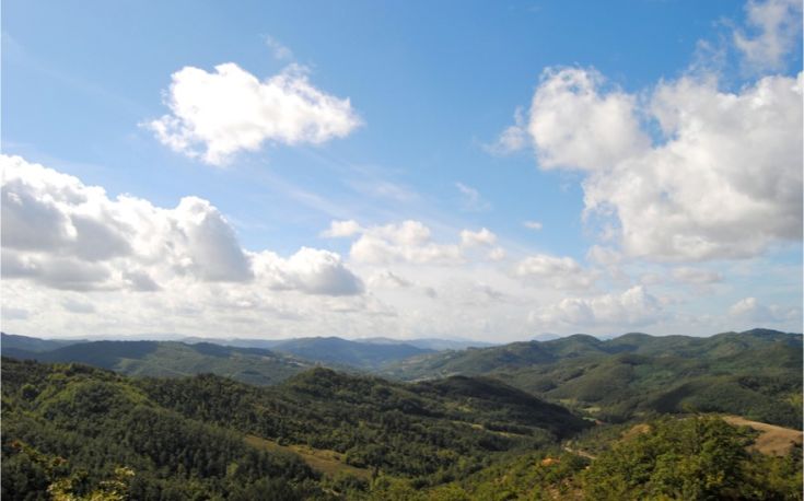 Scena di colline verdi sotto un cielo azzurro, perfetta per rilassarsi nella natura.