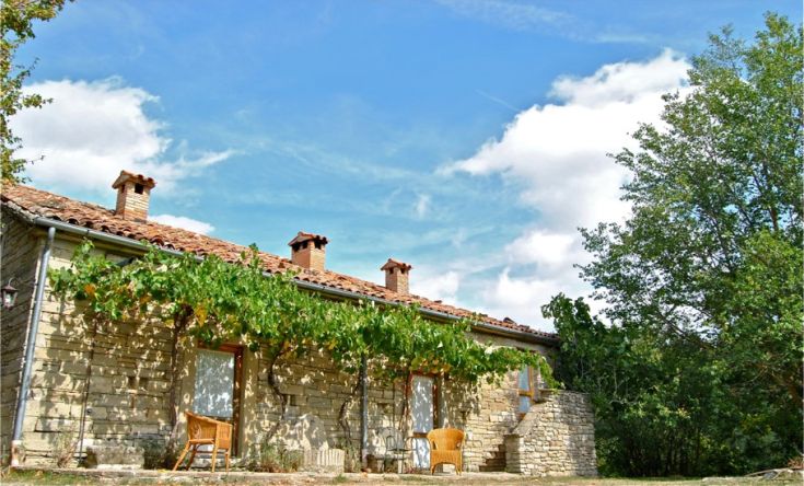 Una casa confortevole circondata dalla natura, con un pergolato di viti e uno scenario di cielo azzurro.