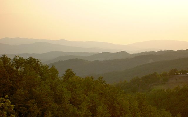 Scena di un tramonto montano, illuminato da tonalità calde che avvolgono l'ambiente.