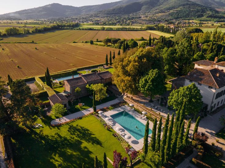 Scena di un edificio con piscina circondato dalla natura. L'ambiente è rilassato e tranquillo.