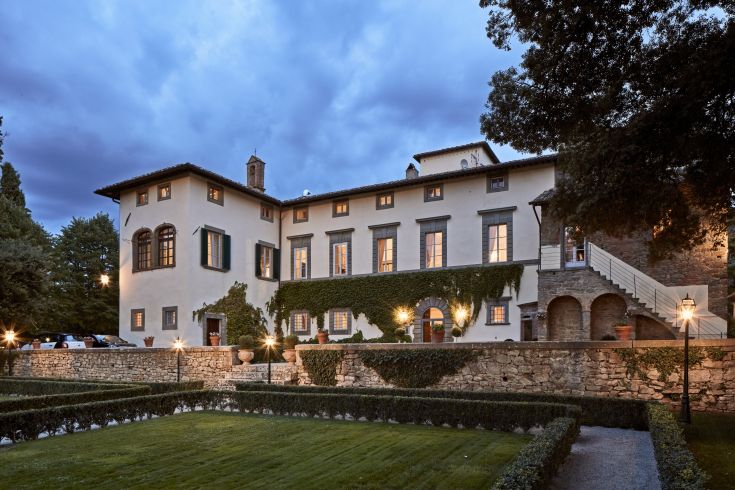 Un edificio circondato da alberi, con una luce calda del tramonto che illumina l'area.