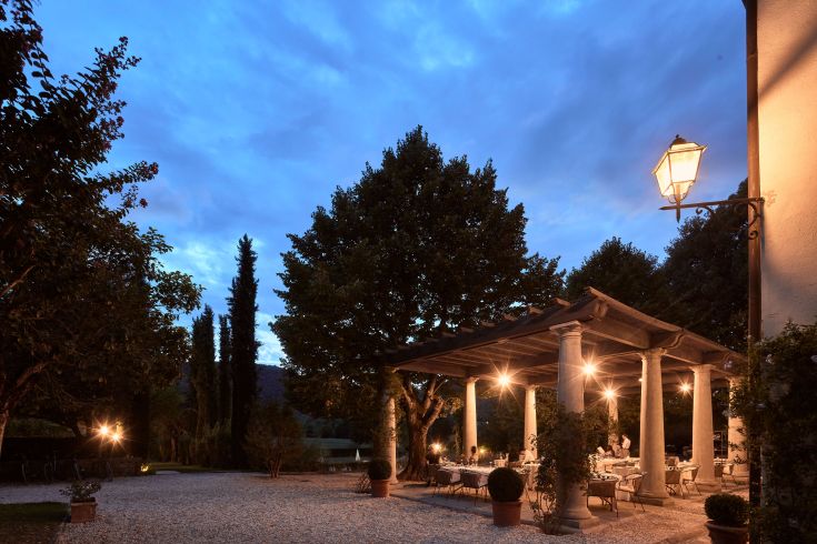 Un'area esterna di un ristorante con tavoli ben disposti, illuminazione soft e un'atmosfera tranquilla.