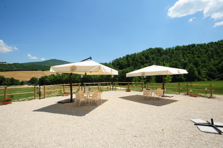 Außenbereich mit Sonnenschirmen und grünem Hintergrund, ideal zum Entspannen und geselligem Beisammensein.