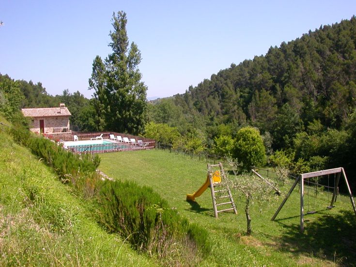 Un agritourisme situé dans les collines, avec piscine et aire de jeux pour enfants, entouré de verdure.