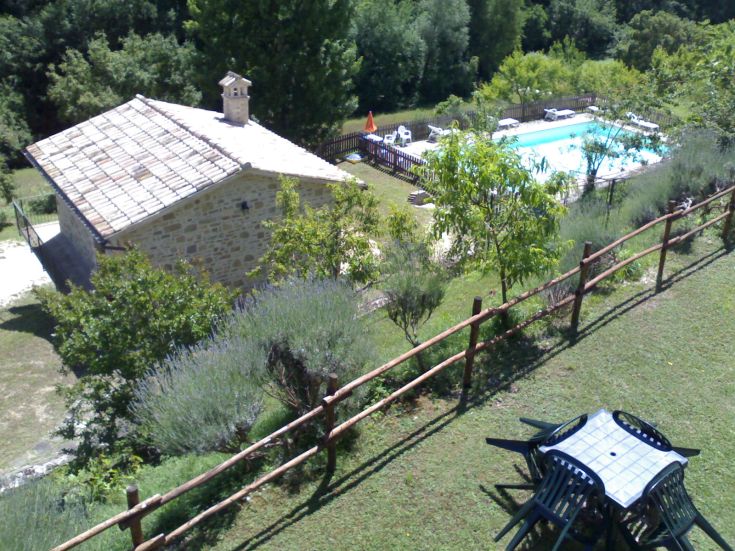 Un agriturismo situé sur une colline, entouré de verdure, avec une piscine et un grand jardin.