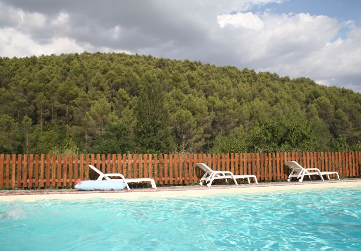Une piscine sereine située dans un paysage vallonné verdoyant, offrant une atmosphère paisible.