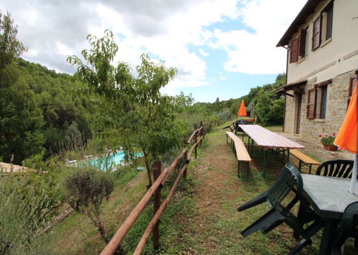 Un agritourisme situé dans une zone verte, avec des tables en plein air et une piscine à proximité.