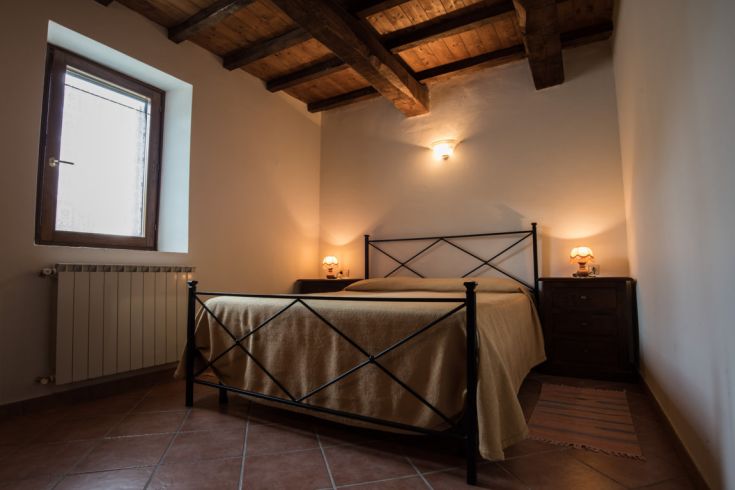 Chambre simple avec un lit double et des meubles en bois, parfaite pour une pause tranquille dans une ferme.