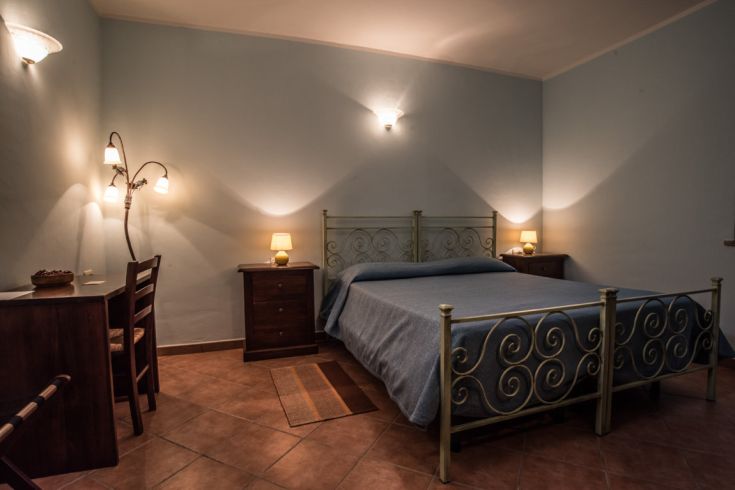 Chambre simple avec un lit double, un bureau et un éclairage doux.