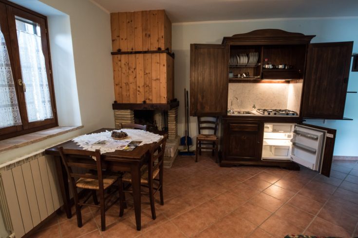 Intérieur d'un agriturismo avec un coin cuisine et une table en bois, décor simple et fonctionnel.