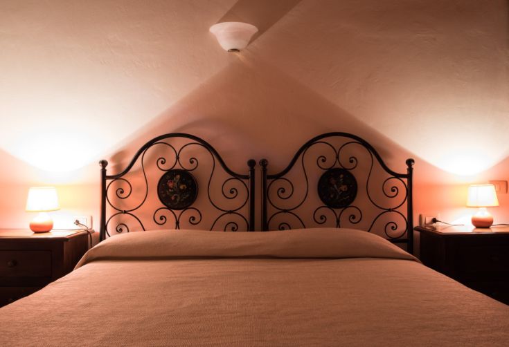 Chambre simple avec un lit double, décorée avec des éléments en fer forgé et un éclairage doux.