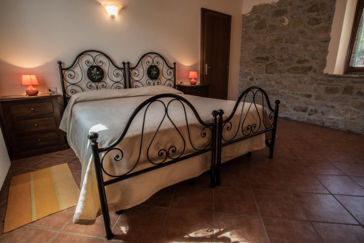 Chambre simple avec des lits en fer forgé et des murs en pierre apparente.