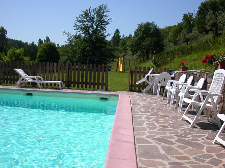 Une piscine verte dans un jardin verdoyant, avec des chaises longues pour se détendre.