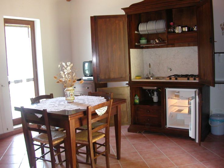 Cuisine simple avec des meubles en bois et une table centrale pour des repas partagés.