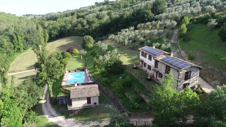 Un agritourisme situé sur une colline, entouré de paysages verdoyants, avec une piscine extérieure.