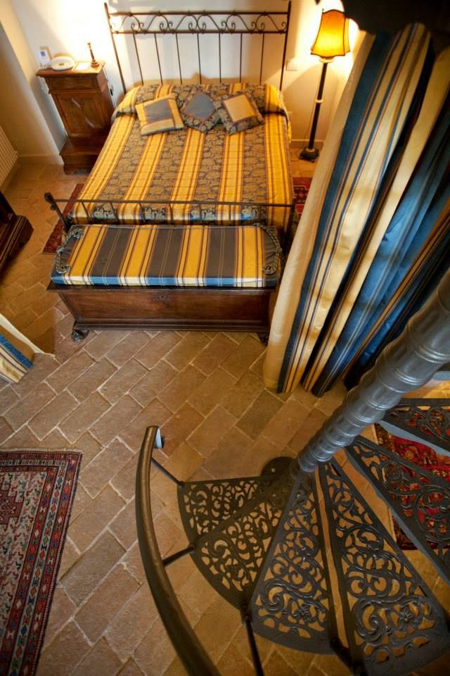 Camera accogliente con letto matrimoniale e scala a chiocciola in un palazzo d'epoca.