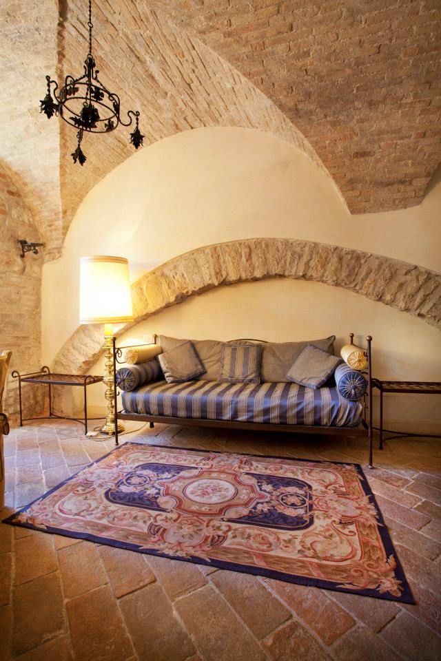 Accogliente soggiorno in un edificio storico con soffitto a volta, divano sobrio e tappeto dai colori vivaci.
