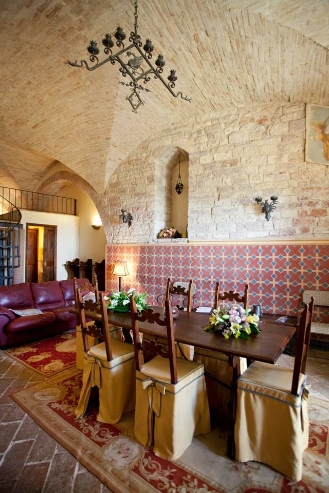 Spaziosa sala da pranzo con soffitti a volta, tavolo in legno e decorazioni ai fiori.